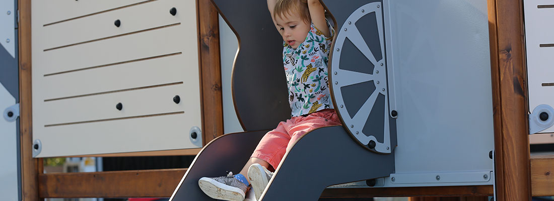 Boy sliding down a pirate themed slide